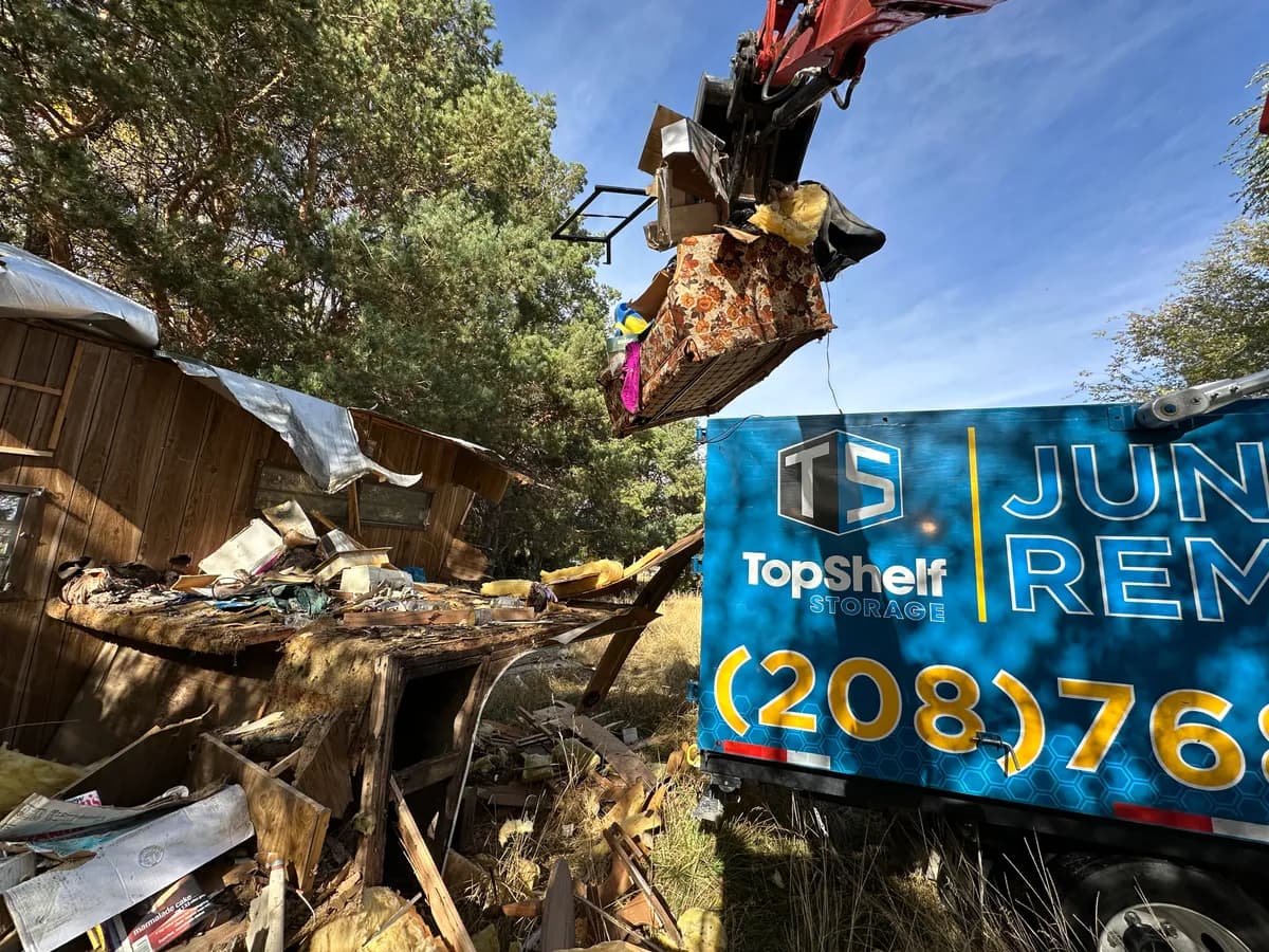Top Shelf grapple arm loading mobile home demolition debris next to the branded truck in Boise Idaho