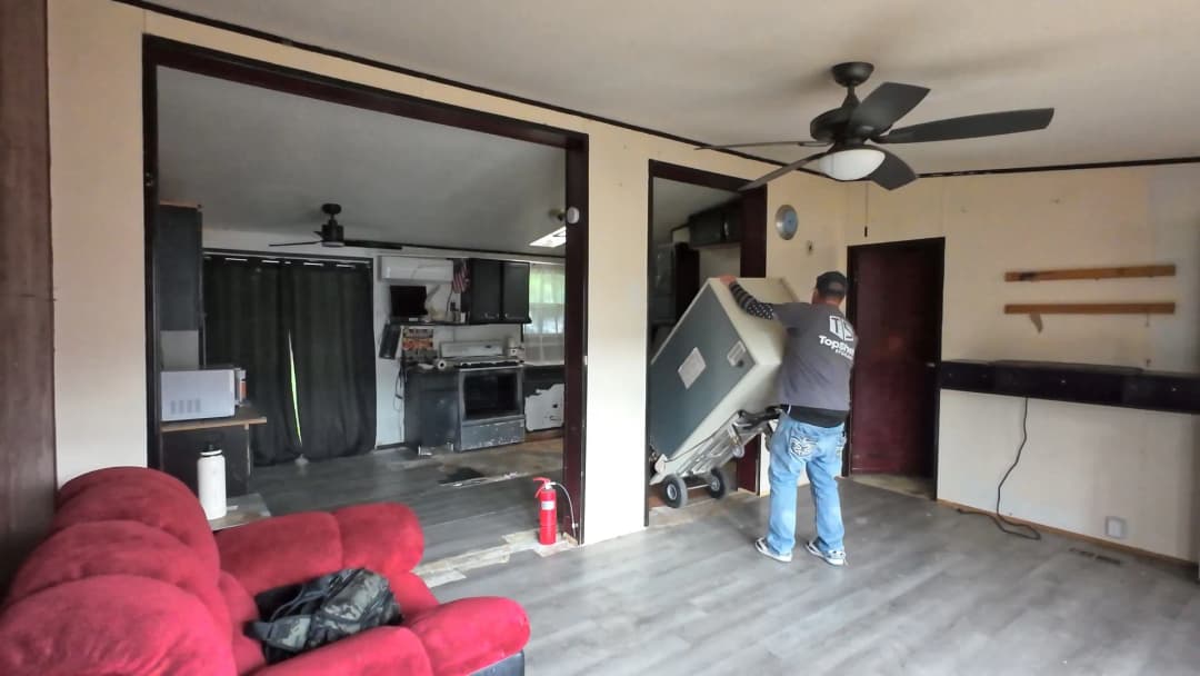 Top Shelf crew member moving a freezer on a dolly through a home interior during a freezer removal job in Meridian Idaho
