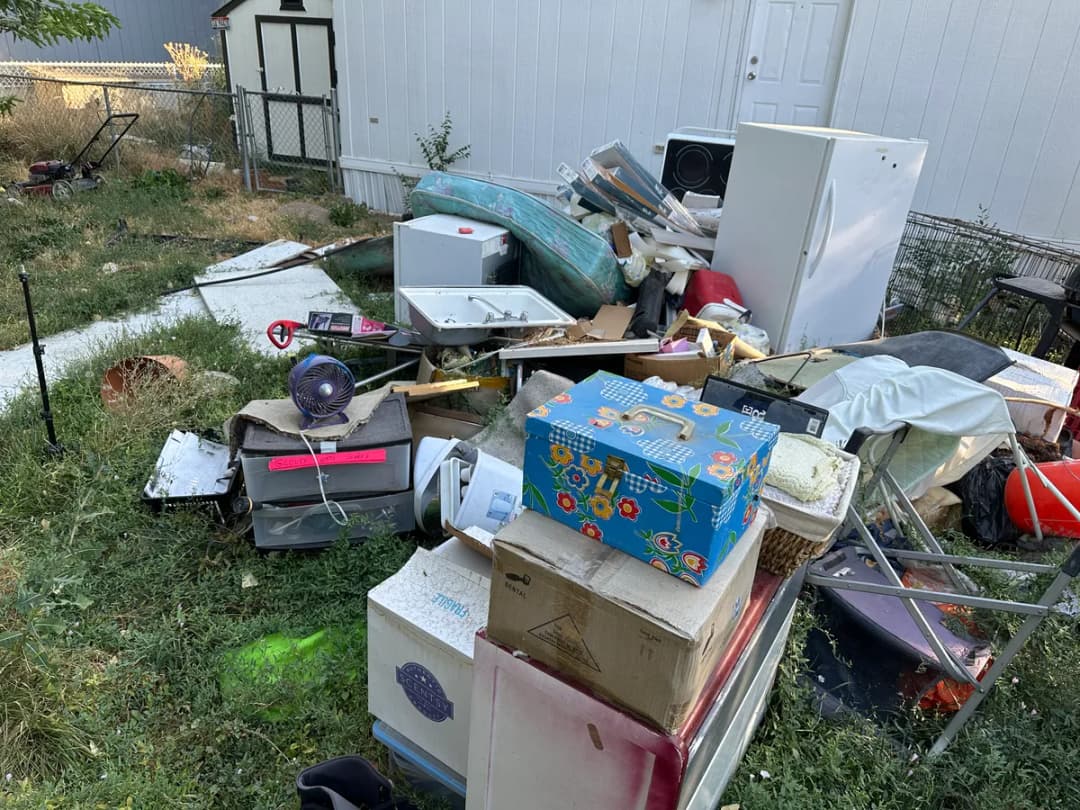 Household junk piled up in a yard during an eviction cleanout