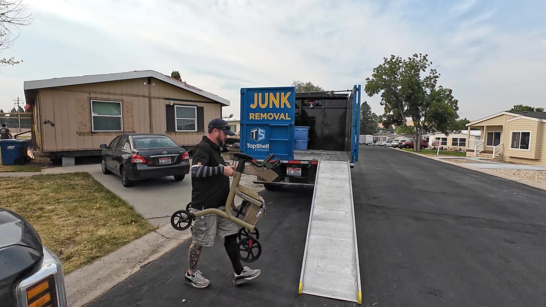 Top Shelf crew member carrying a medical walker toward the branded junk removal truck during a medical equipment removal job in Meridian Idaho