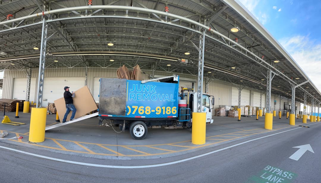 Top Shelf crew member loading large cardboard sheets into the branded junk removal truck at a warehouse in Nampa Idaho