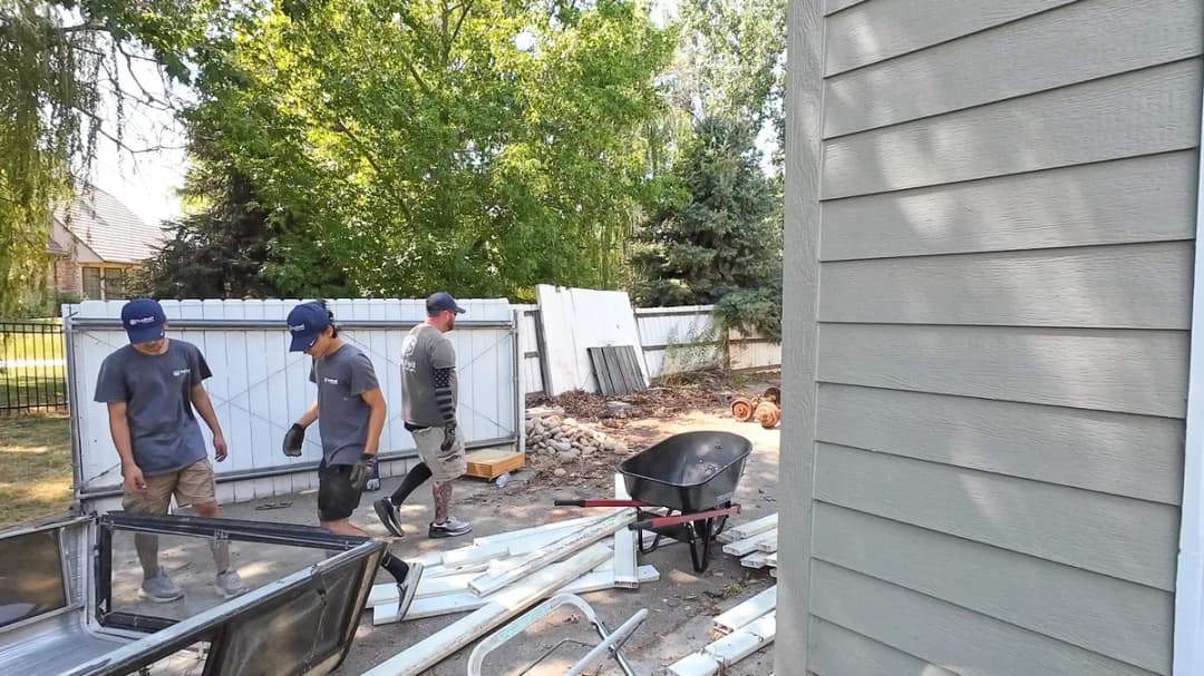 Top Shelf crew clearing construction debris including old windows and trim from a residential backyard in Caldwell Idaho