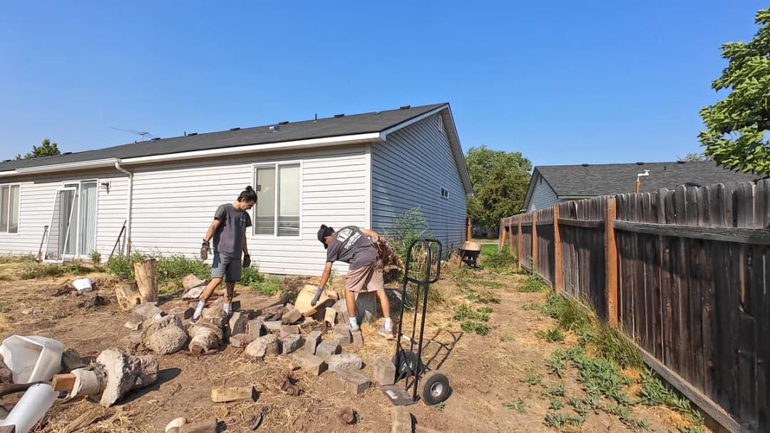 Top Shelf crew clearing concrete and wood debris from a backyard during a yard cleanout in Meridian Idaho