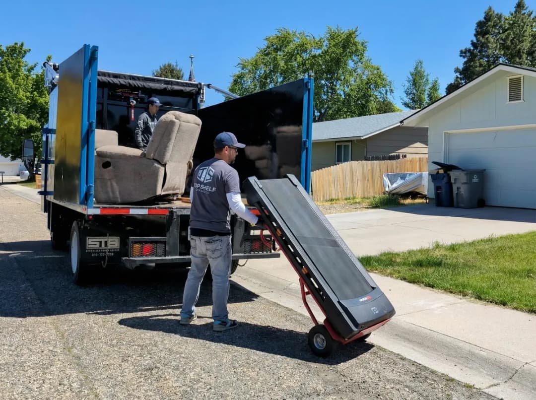 Top Shelf crew member loading a treadmill on a dolly into the junk removal truck in a residential neighborhood in Eagle Idaho