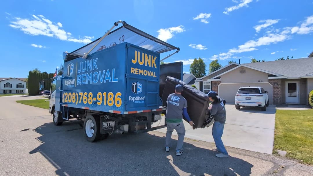 Two Top Shelf crew members loading a couch into the branded junk removal truck in Meridian Idaho