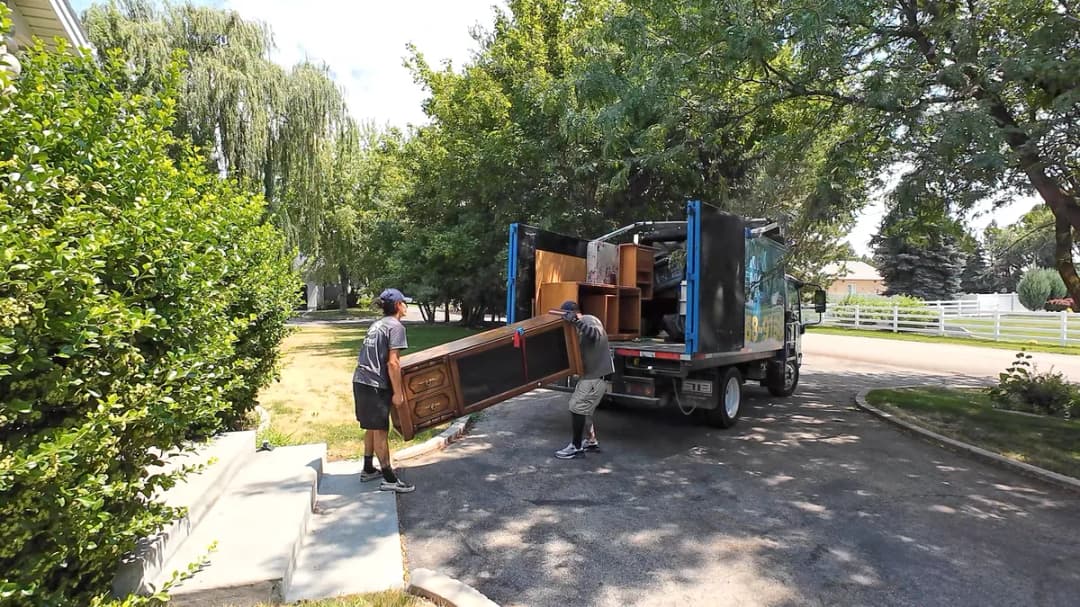 Top Shelf crew loading a dresser into the junk removal truck