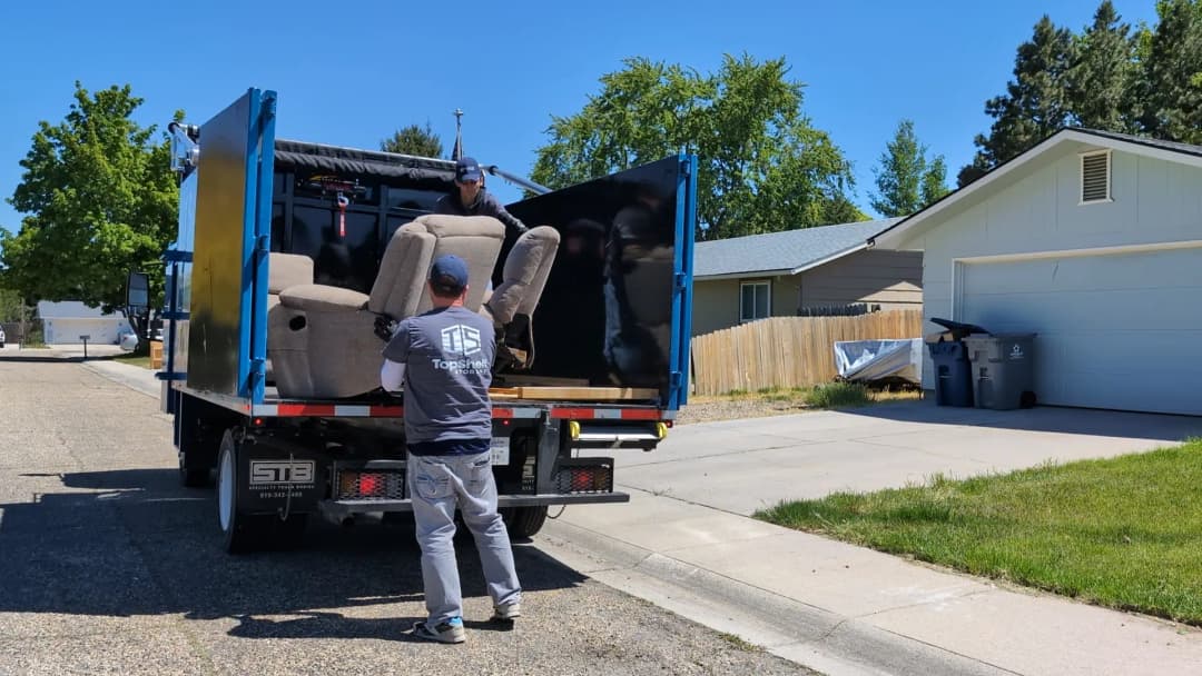 Top Shelf crew member loading a recliner into the junk removal truck