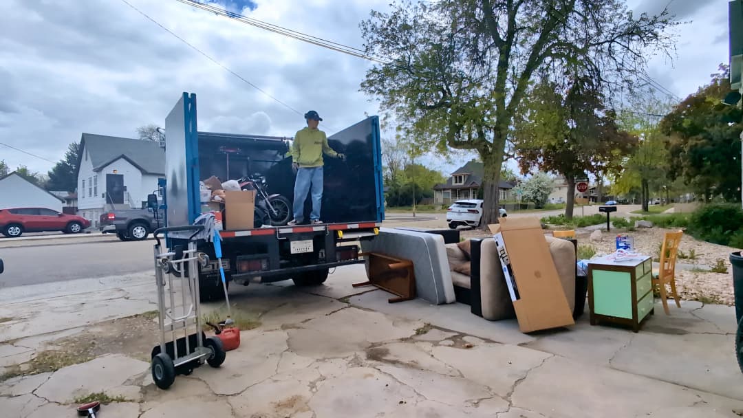 Top Shelf crew loading a motorcycle mattress couch and chairs into the junk removal truck during a curbside pickup in Eagle Idaho