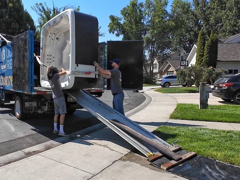 Two Top Shelf crew members loading a hot tub onto the junk removal truck in Happy Valley, Nampa, Idaho