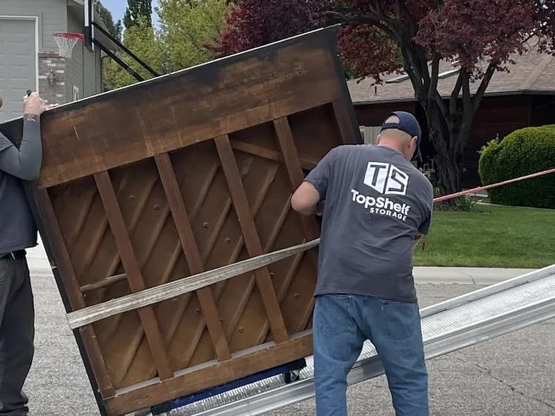 Top Shelf crew loading an upright piano onto a truck ramp during a piano removal job in Boise, Idaho