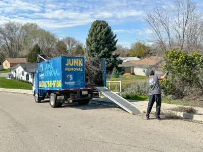 Top Shelf Junk Removal crew member loading branches with truck ramp in Meridian Idaho