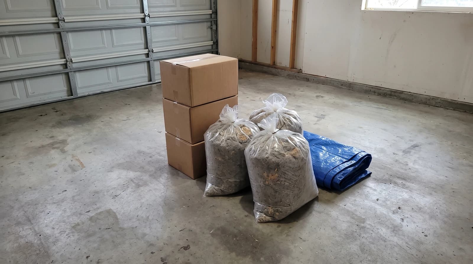 Sealed cardboard boxes and bagged old insulation from an attic cleanout on a garage floor in Star, Idaho