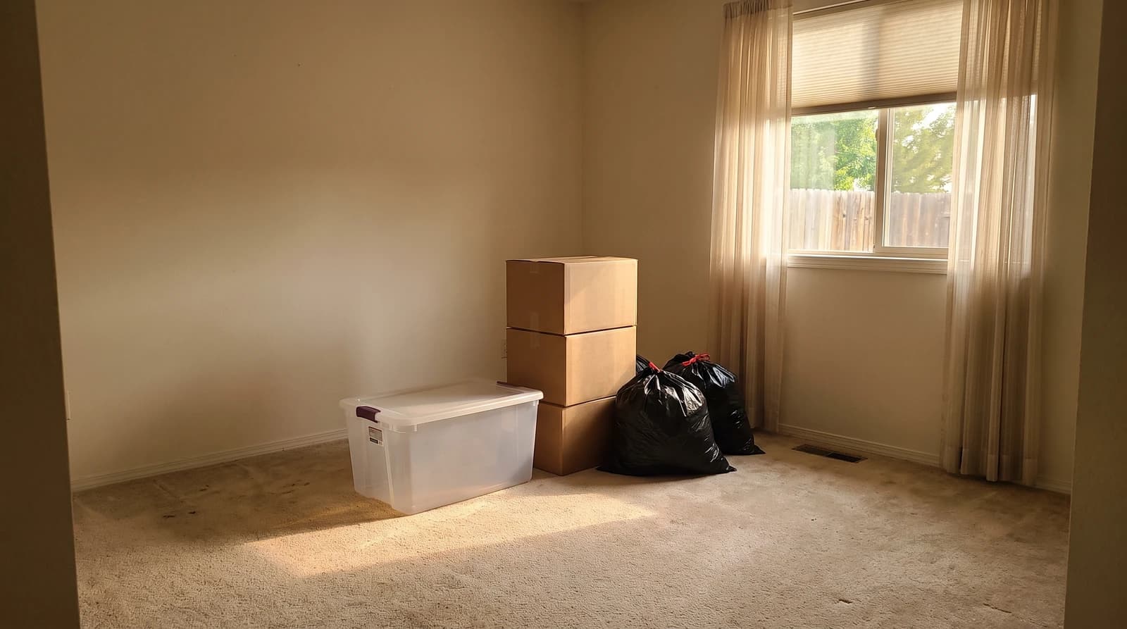 Sorted boxes, a storage tote and bagged items in a cleared-out bedroom during an empty nest cleanout in Eagle, Idaho