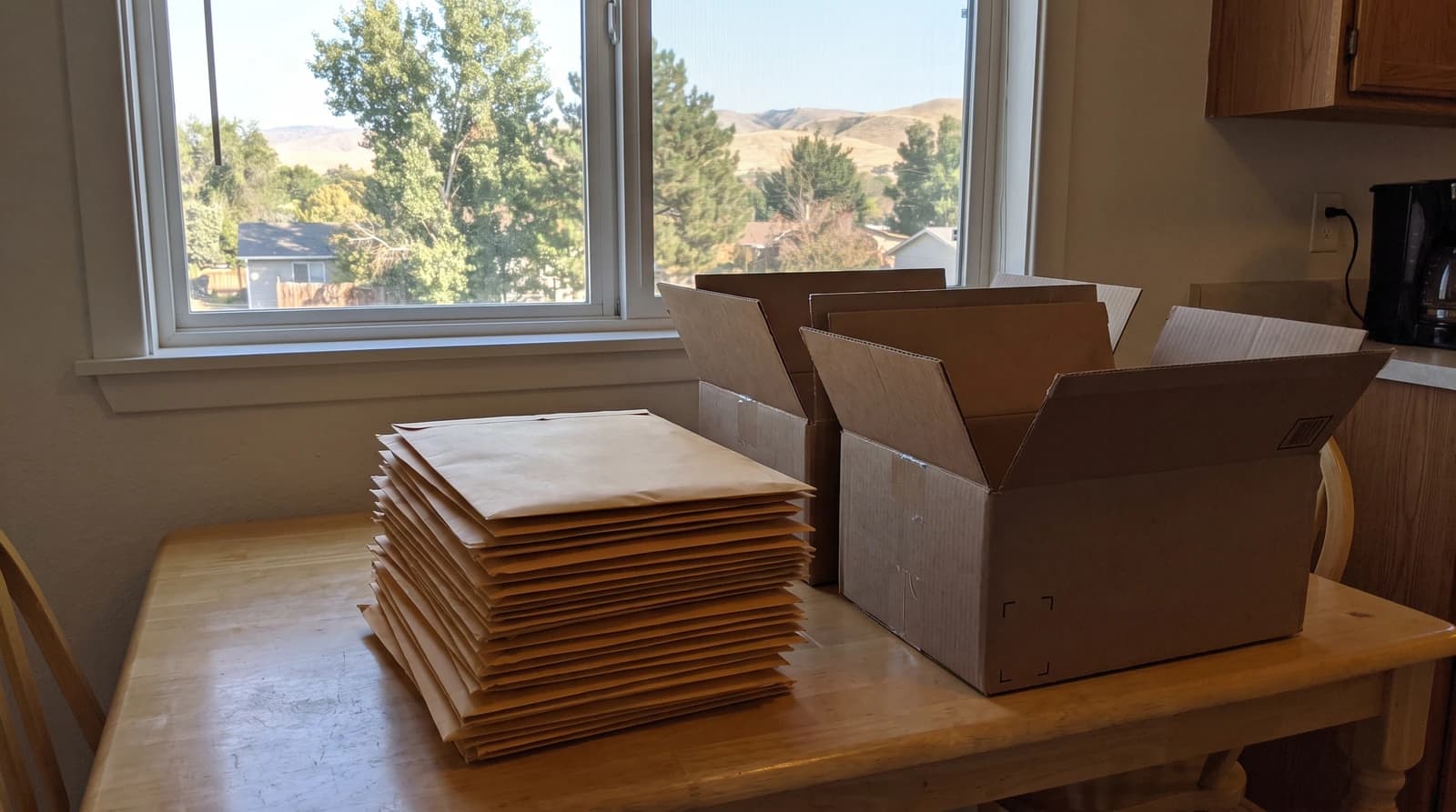 Stack of plain envelopes and two empty cardboard bins on a kitchen table during an estate cleanout at a home in Star, Idaho