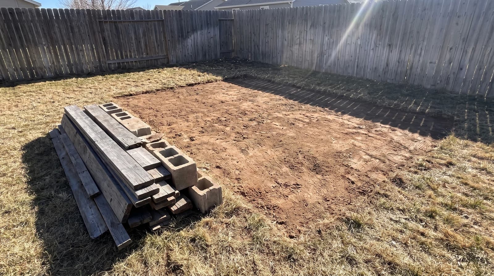 Bare dirt and a neat stack of old shed boards and concrete blocks after a shed demolition in a Nampa, Idaho backyard