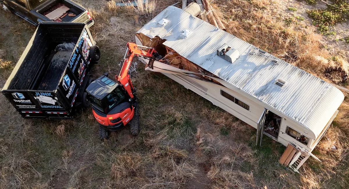 Top Shelf excavator demolishing a camper