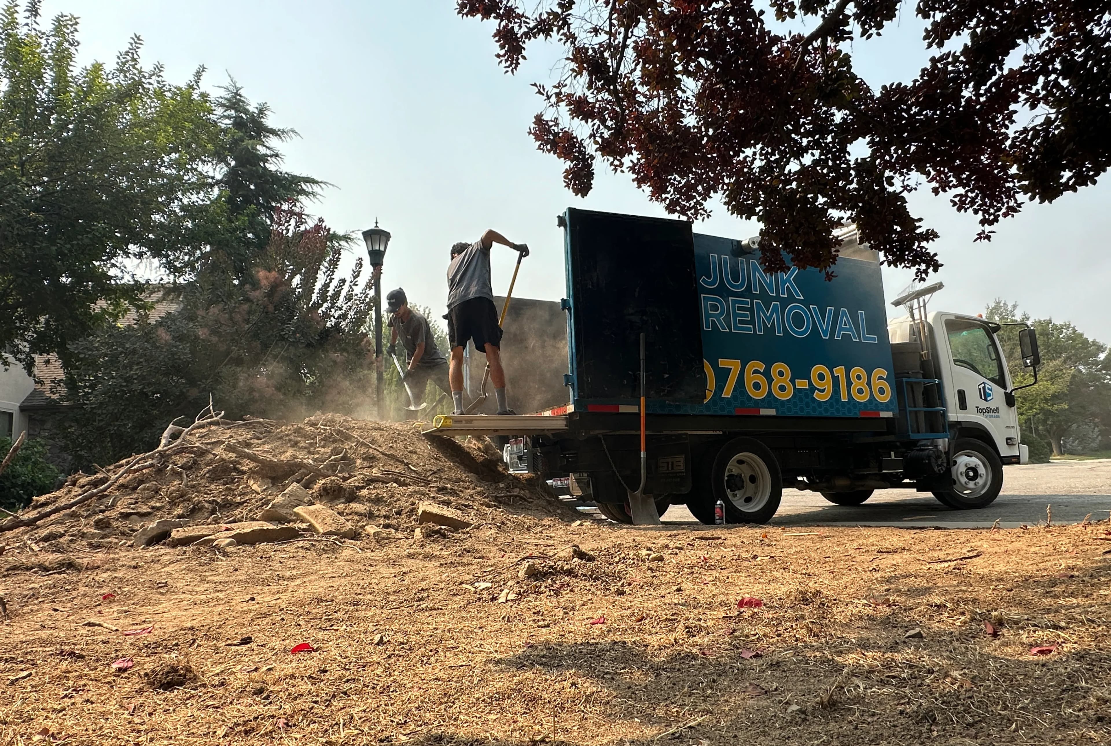 Top Shelf crew shoveling dirt into the branded junk removal truck at a residential property in Boise Idaho