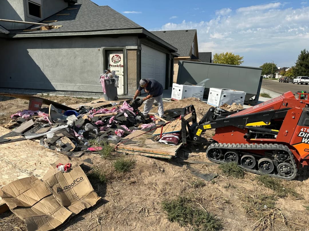 Top Shelf skid steer cleaning up construction debris at a job site