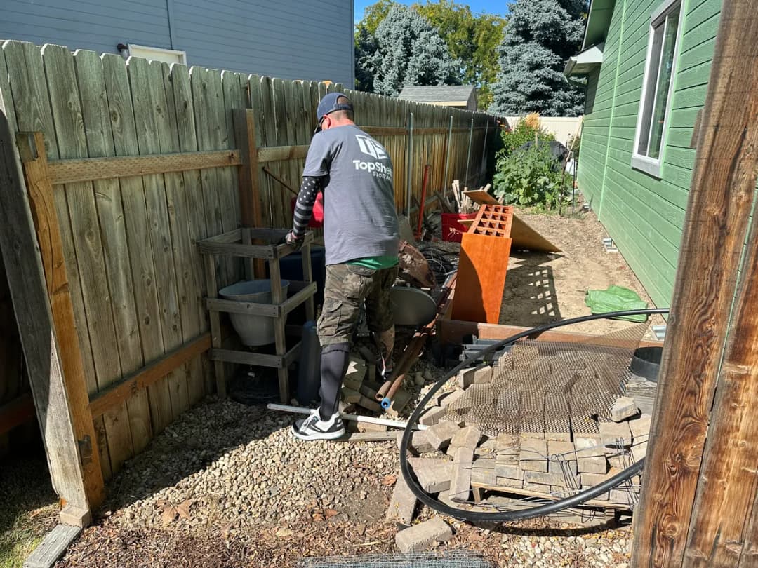Top Shelf crew member clearing bricks pavers and yard debris from a residential backyard in Nampa Idaho