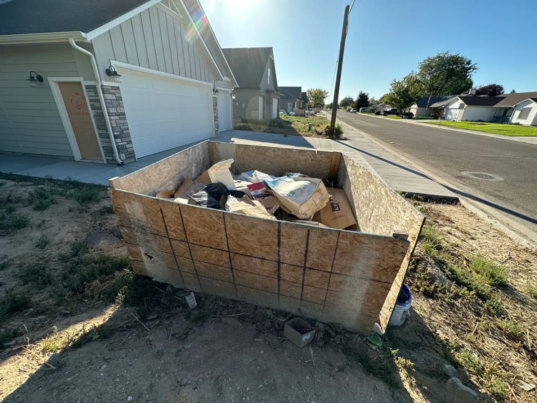 Plywood dumpster enclosure filled with construction debris at a new build site in Boise Idaho