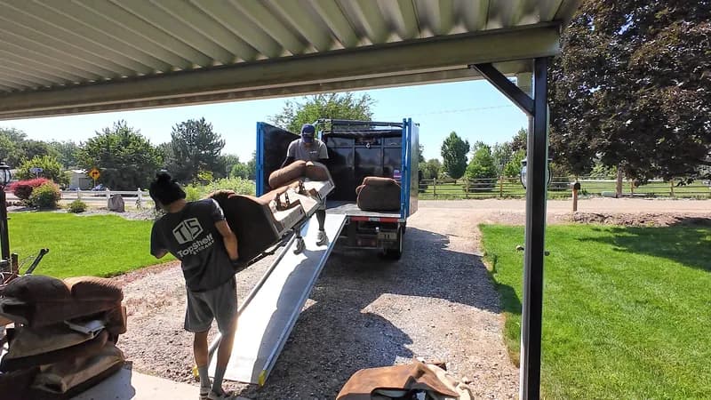 Top Shelf crew pushing a couch up the truck ramp under a carport in Eagle Idaho