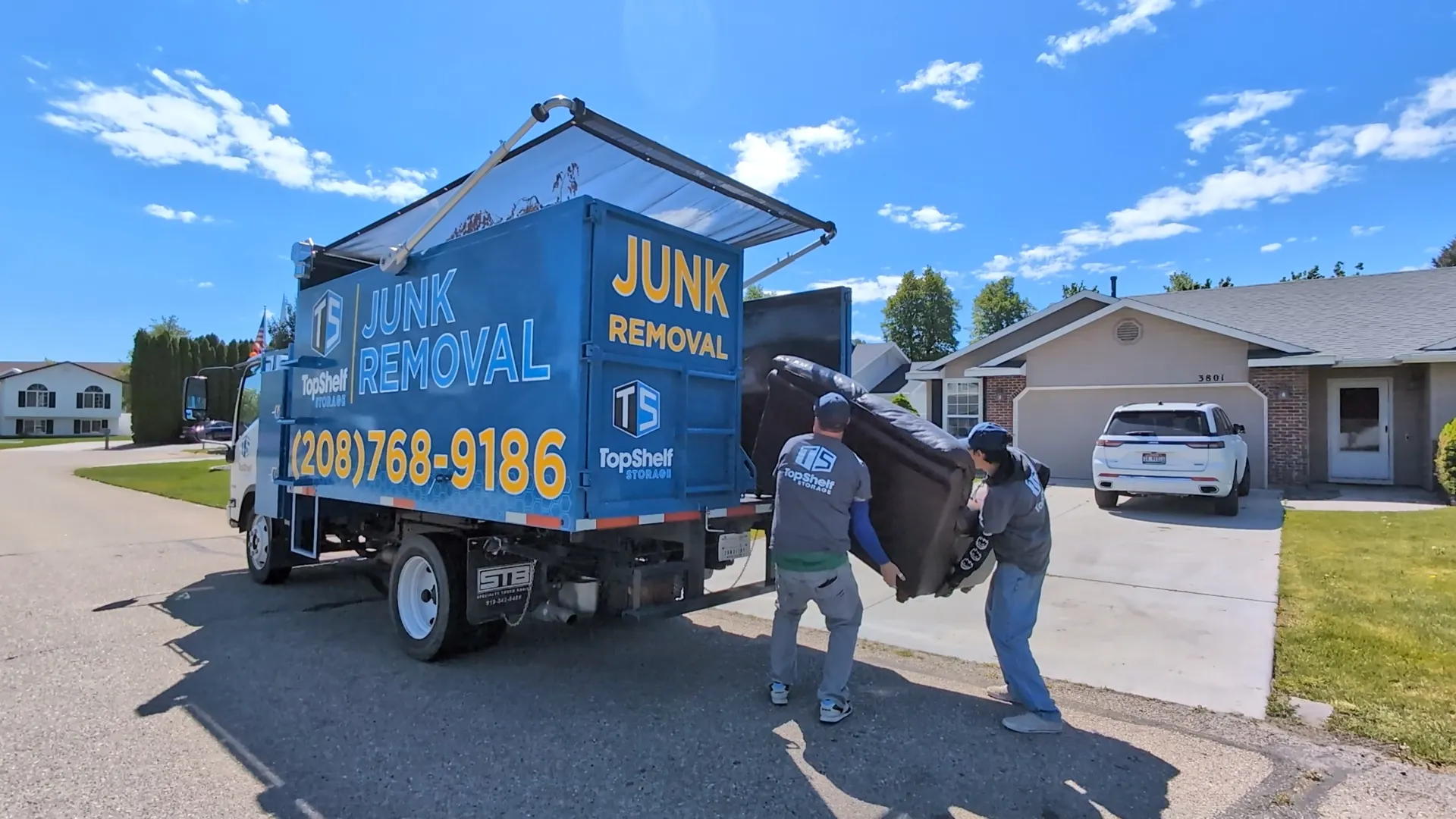 Two Top Shelf crew members loading a couch into the branded junk removal truck in Meridian Idaho