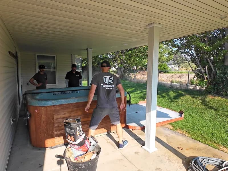 Three Top Shelf crew members preparing to move a hot tub from under a covered patio in Caldwell Idaho