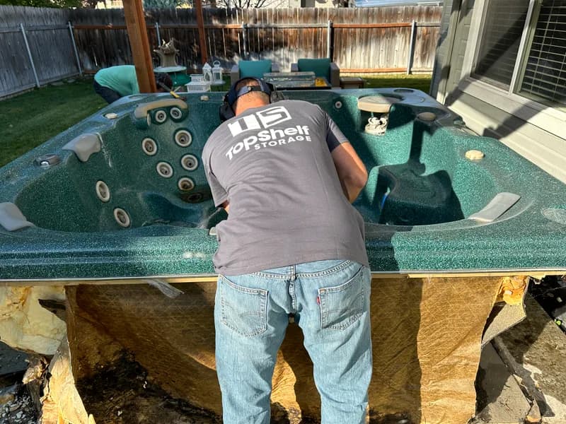 Top Shelf worker using a saw to cut apart a hot tub in Nampa Idaho