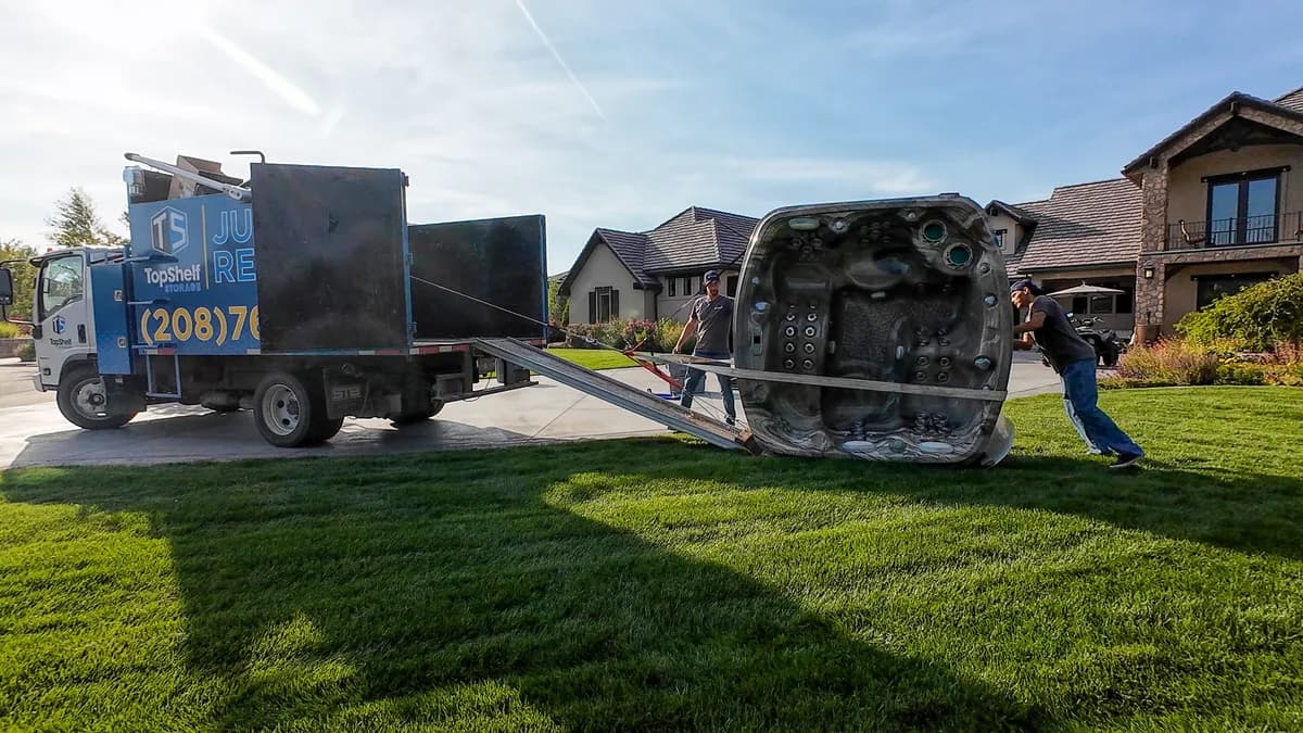 Two crew members guiding a hot tub up the ramp into the branded truck in Nampa Idaho