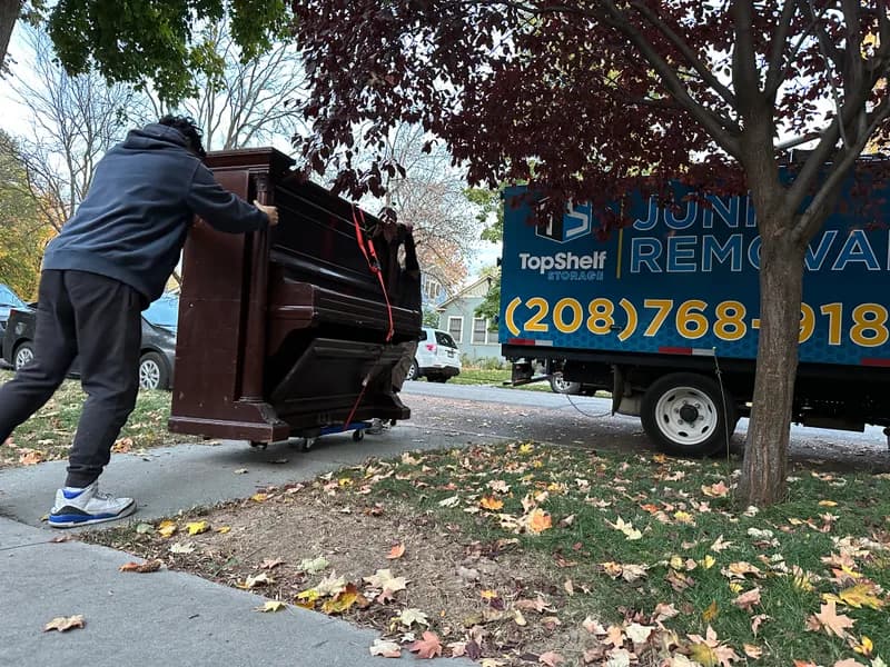 Top Shelf crew pushing a piano on a dolly toward the truck in Nampa Idaho