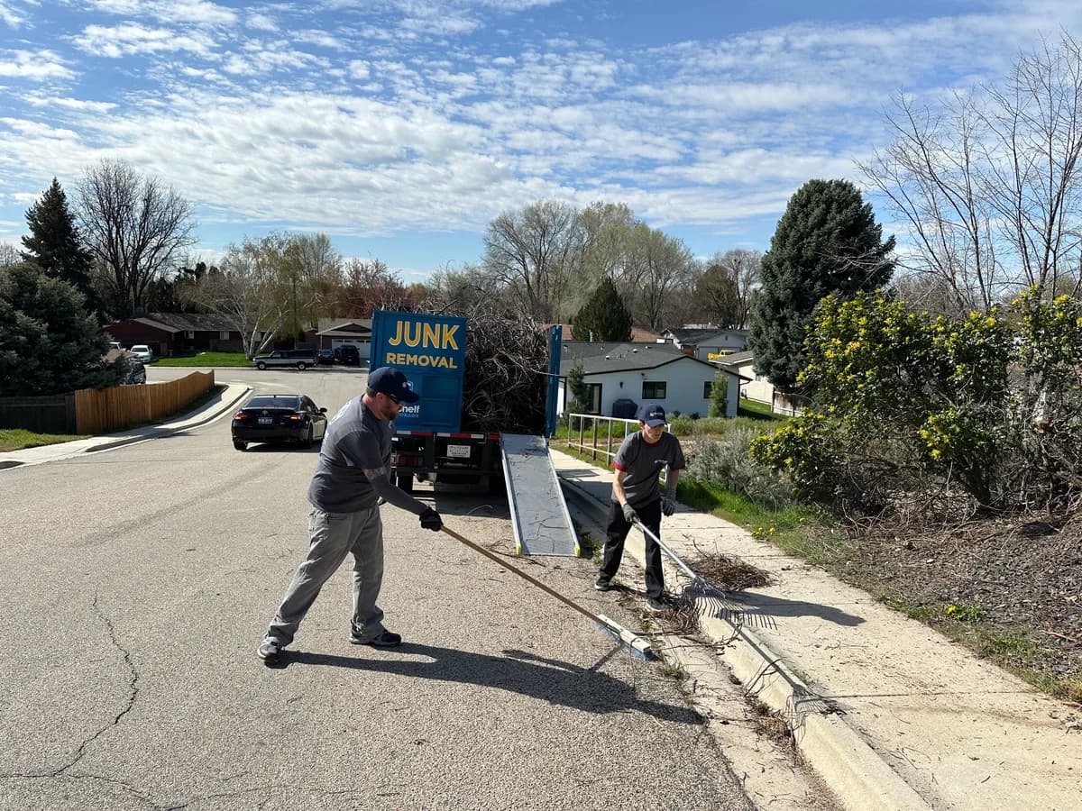 Top Shelf crew raking up tree branches during a yard debris removal job in Middleton Idaho